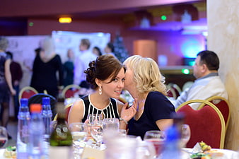 Two women sharing a kiss at a formal corporate event