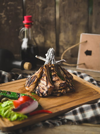 Grilled lamb chops on wooden board with vegetables