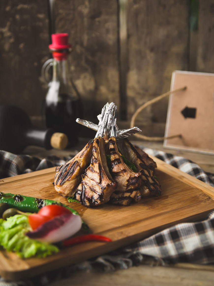 Grilled lamb chops on wooden board with vegetables