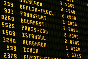 Close-up of airport departure board with flight destinations and times