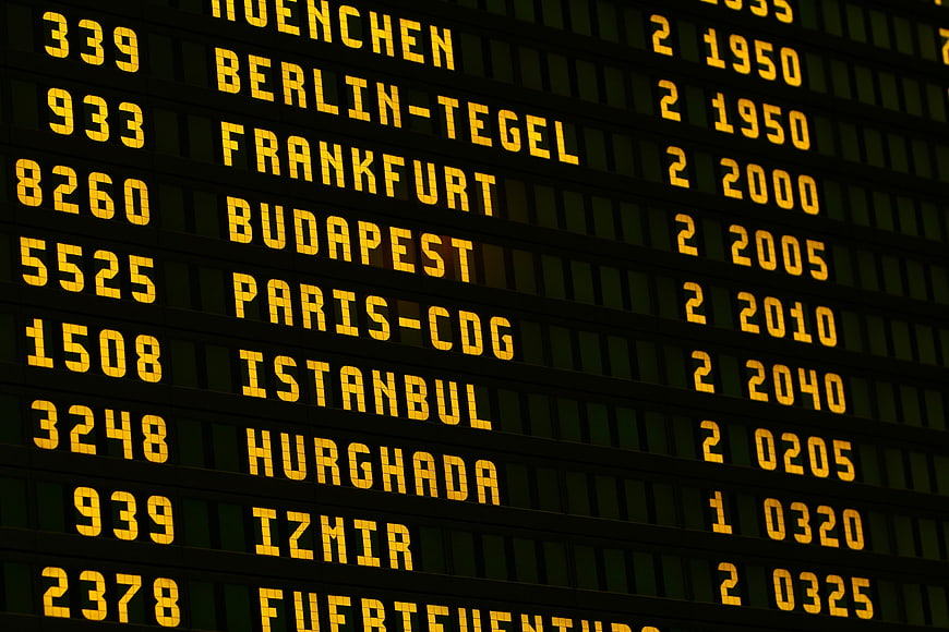 Close-up of airport departure board with flight destinations and times