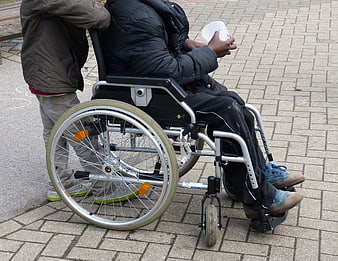 Child Pushing Person in Wheelchair on Paved Path