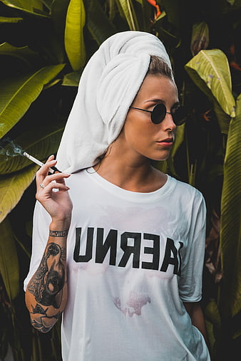 Woman with towel on head smoking cigarette outdoors