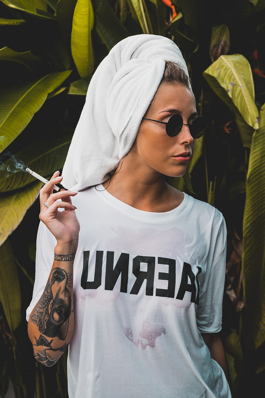 Woman with towel on head smoking cigarette outdoors