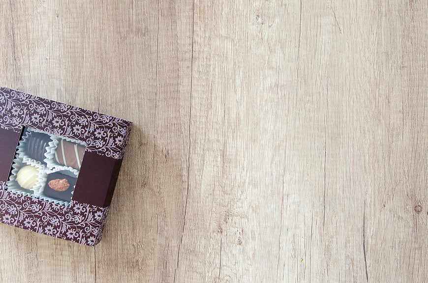 Box of assorted chocolates on light wooden background