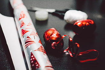 Christmas Wrapping Supplies with Red Ribbon on Dark Table