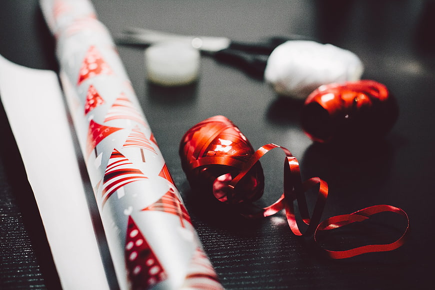 Christmas Wrapping Supplies with Red Ribbon on Dark Table
