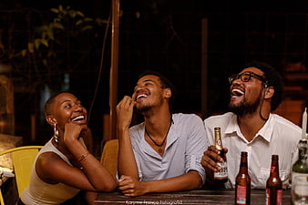 Three Friends Laughing Together at Night with Beer