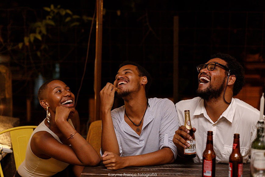 Three Friends Laughing Together at Night with Beer