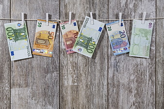 Euro banknotes hanging on clothesline against rustic wood