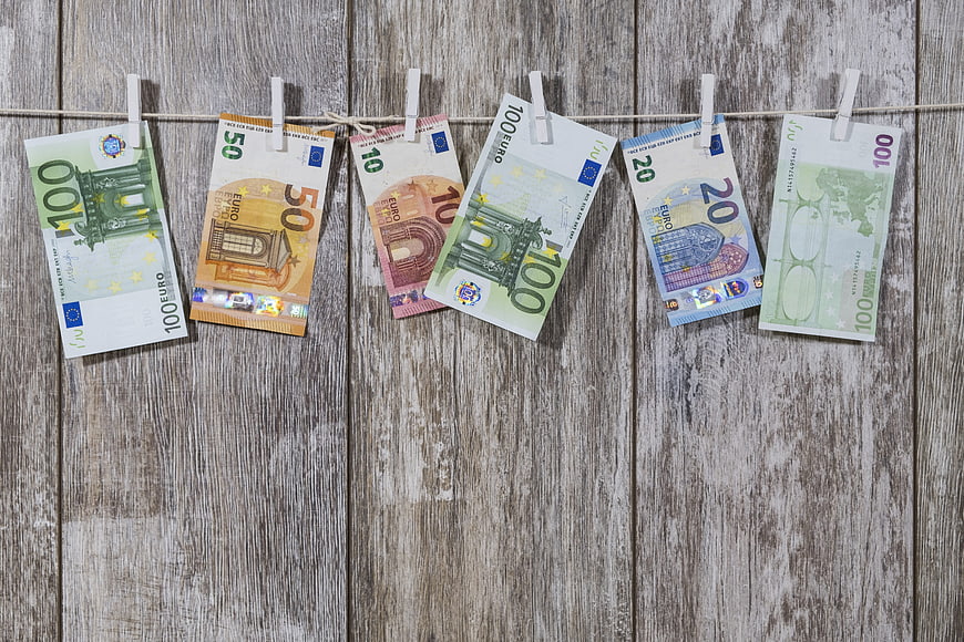 Euro banknotes hanging on clothesline against rustic wood