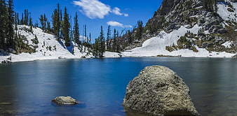Serene Alpine Lake with Snowy Slopes and Pine Trees