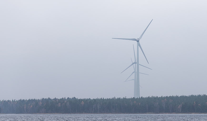 Wind turbines in foggy landscape with forest and water