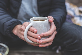 Person Holding Warm Coffee Mug in Winter Jacket