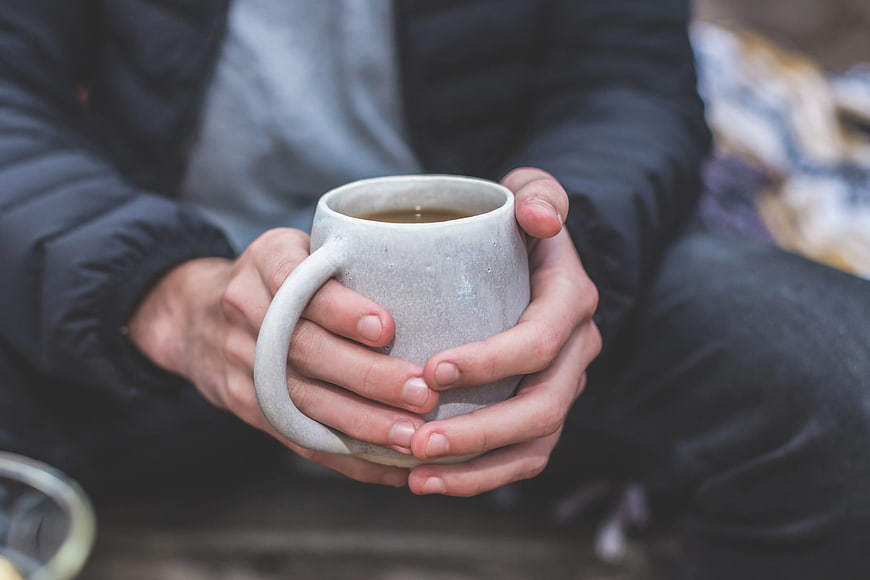 Person Holding Warm Coffee Mug in Winter Jacket