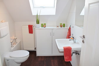 Modern white attic bathroom with skylight and red accents