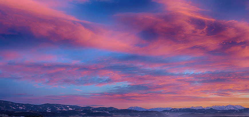 Vibrant Pink and Purple Sunset Sky Over Snowy Mountain Range