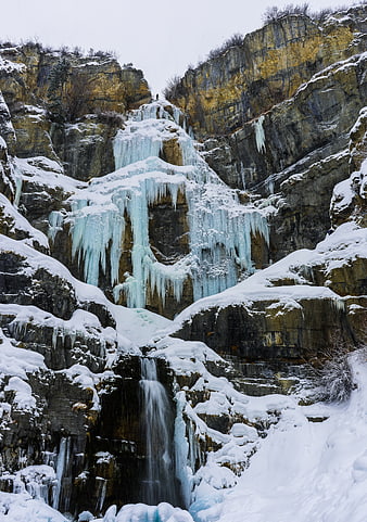 Frozen waterfall cascading down snowy winter cliffs