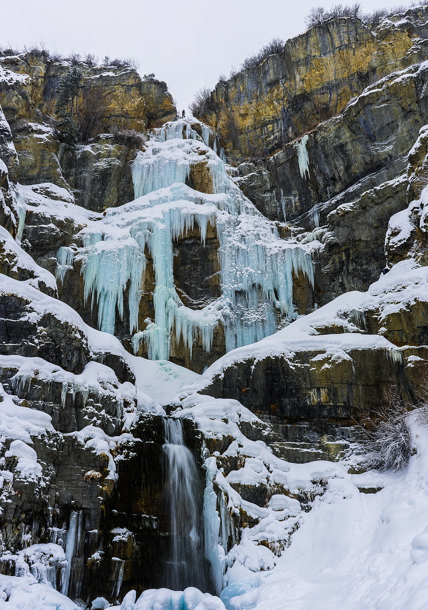 Frozen waterfall cascading down snowy winter cliffs