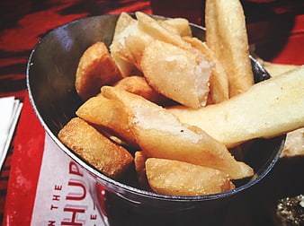 Close-up of golden fried potato wedges in a black bowl