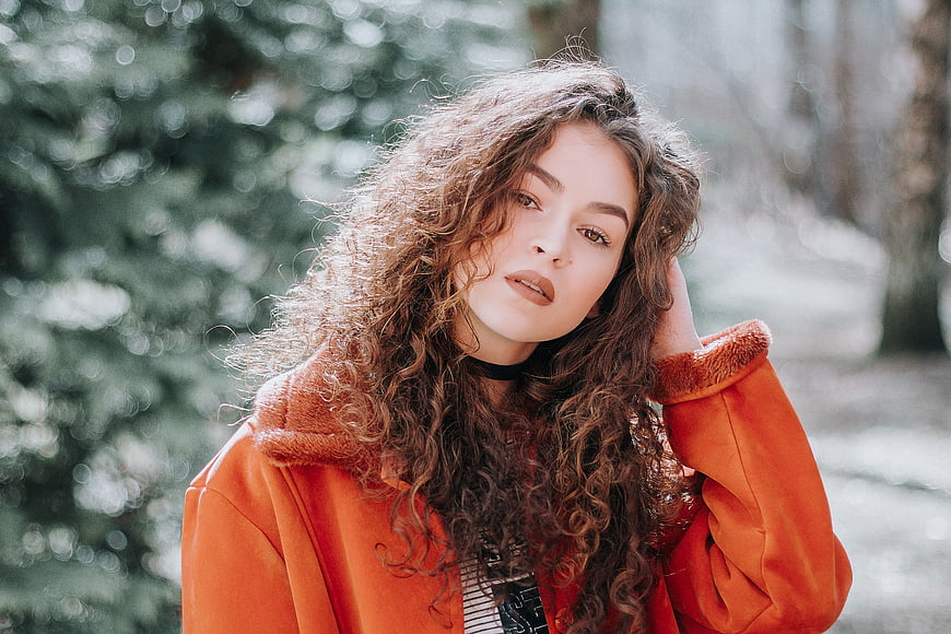 Portrait of Young Woman with Curly Hair in Orange Coat