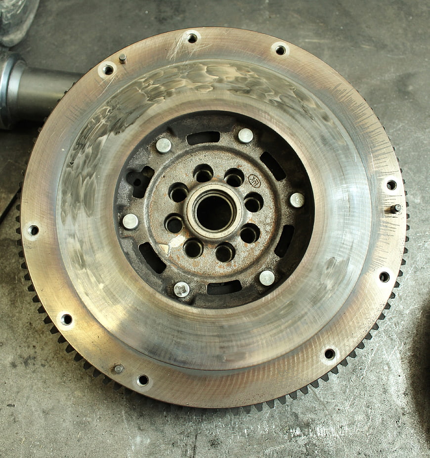 Automotive Flywheel Sprocket Close Up On Concrete Workshop Floor