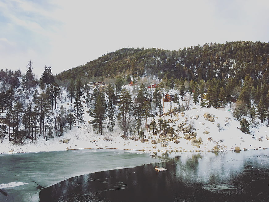 Snowy Mountain Lake with Pine Trees and Cabins