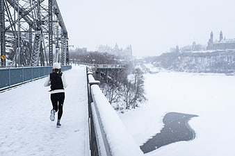 Woman Running on Snowy Bridge in Winter City