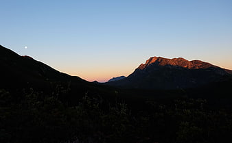 Alpenglow on Mountain Peak at Sunset with Moon