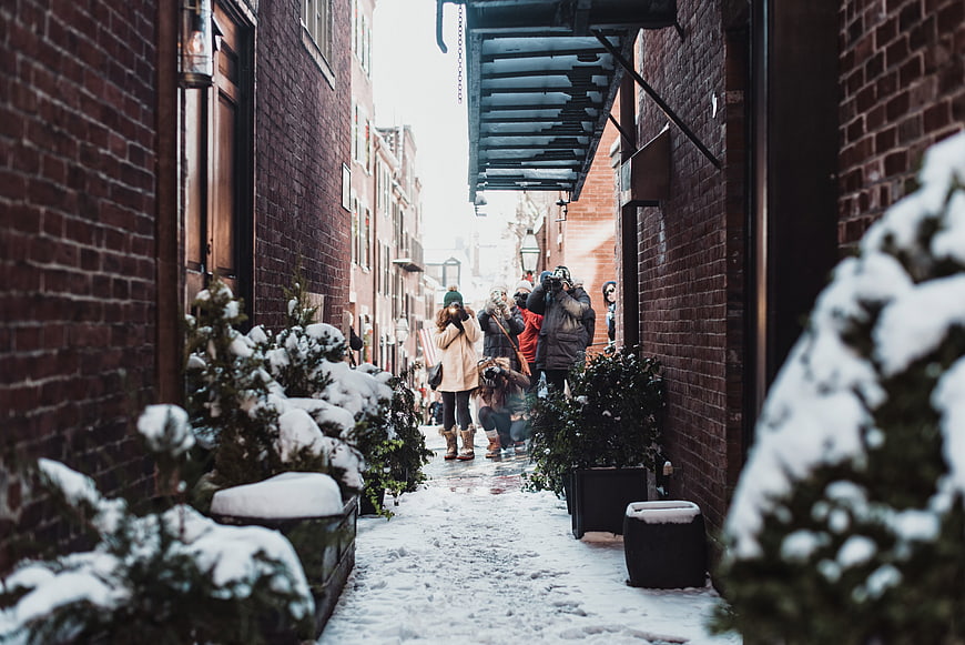 People taking photos in snowy brick alleyway