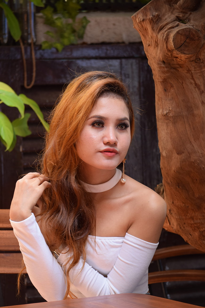 Portrait of young woman with long wavy hair in white top