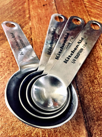 Nested stainless steel measuring spoons on rustic wood