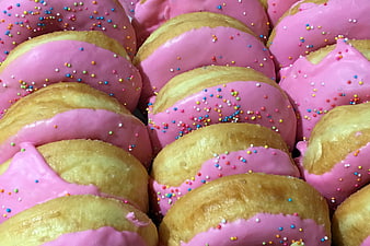 Close-up of pink glazed donuts with colorful sprinkles