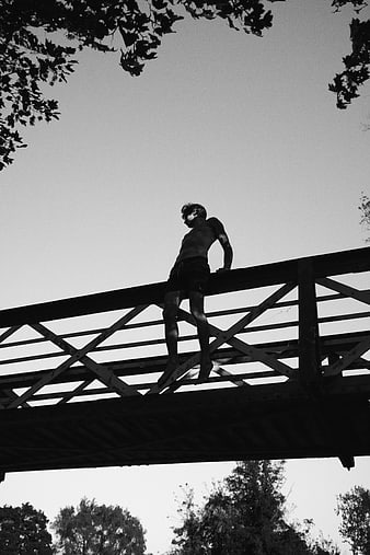 Silhouette of Man Standing on Bridge Railing