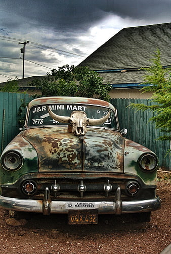 Rusty vintage car with longhorn skull hood ornament