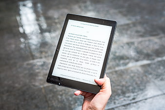 Hand holding Kobo e-reader displaying French text on rainy street