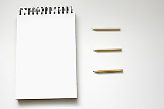 Minimalist spiral notebook and pencils on white background