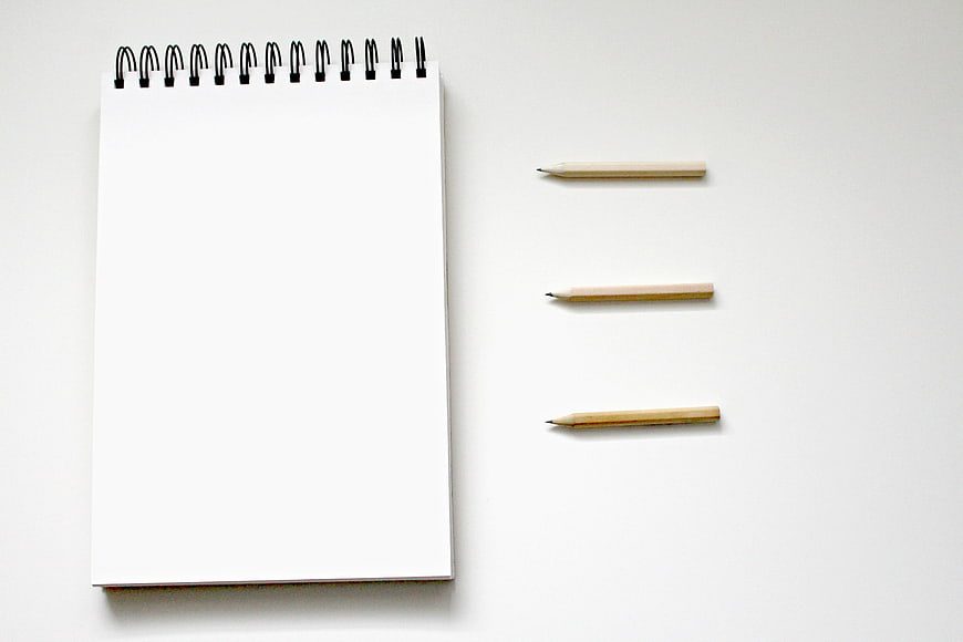 Minimalist spiral notebook and pencils on white background
