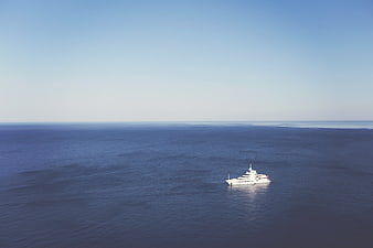 Aerial view of a white luxury yacht sailing on the open ocean