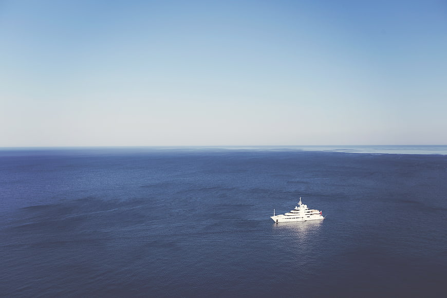 Aerial view of a white luxury yacht sailing on the open ocean