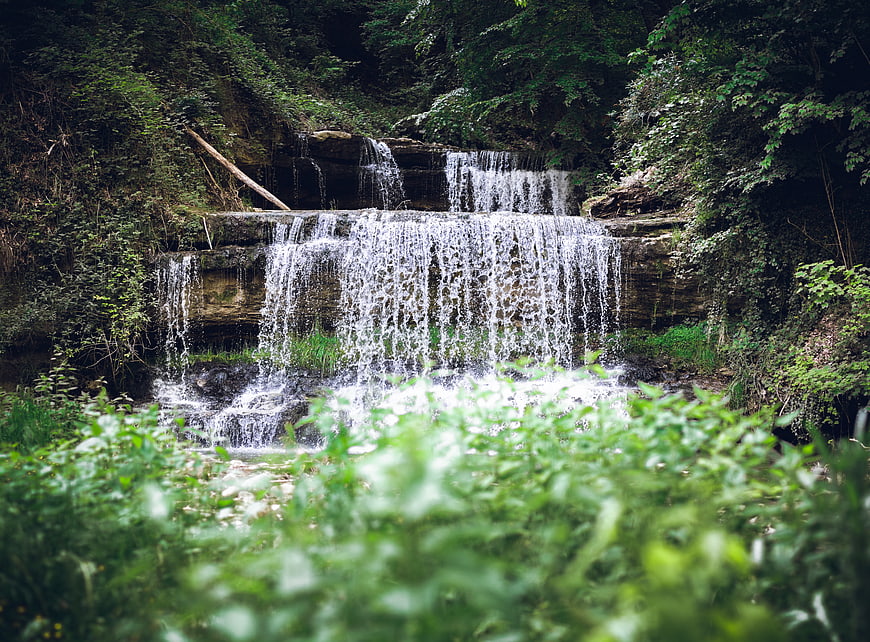 Lush green waterfall cascading through dense forest foliage