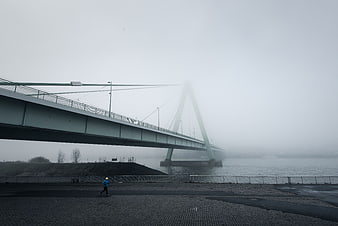 Lone Jogger Running Under Foggy Bridge