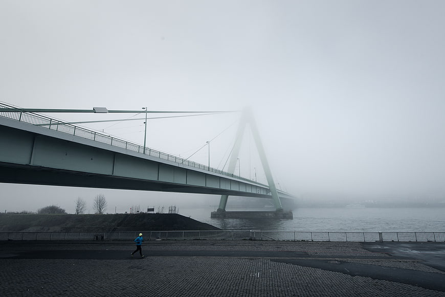 Lone Jogger Running Under Foggy Bridge