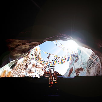 View from dark cave looking out at prayer flags and sunlight