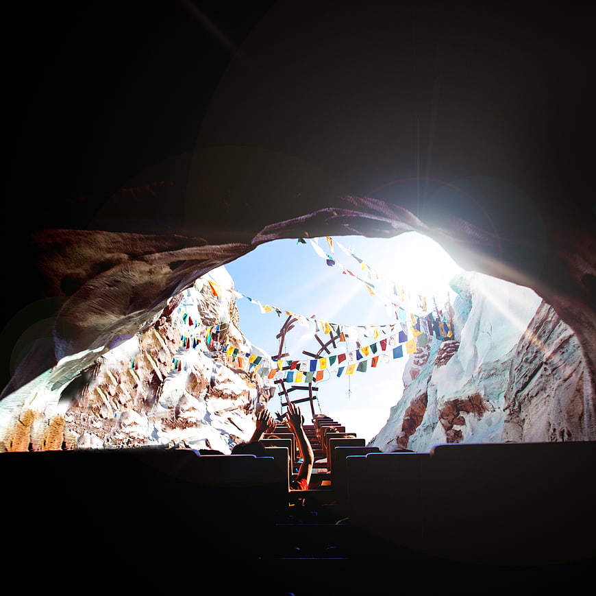 View from dark cave looking out at prayer flags and sunlight