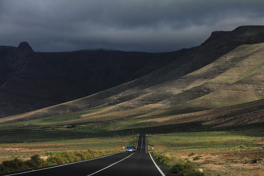 Dramatic Mountain Landscape with Winding Road and Dark Stormy Sky