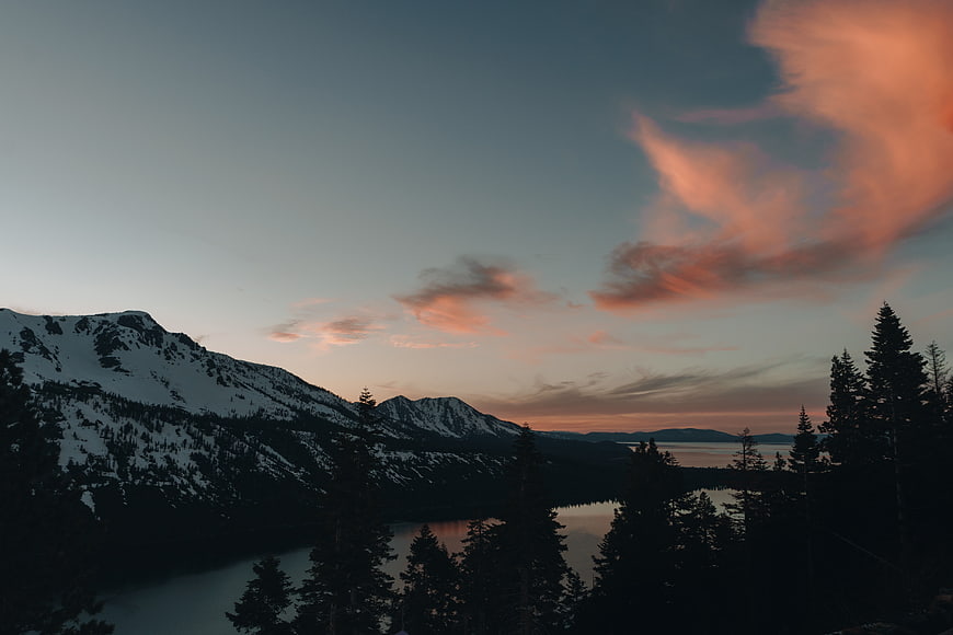 Snowy Mountain Landscape with Pink Sunset Clouds and Lake