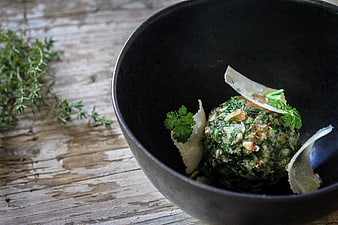 Gourmet spinach dumpling in black bowl on rustic wood