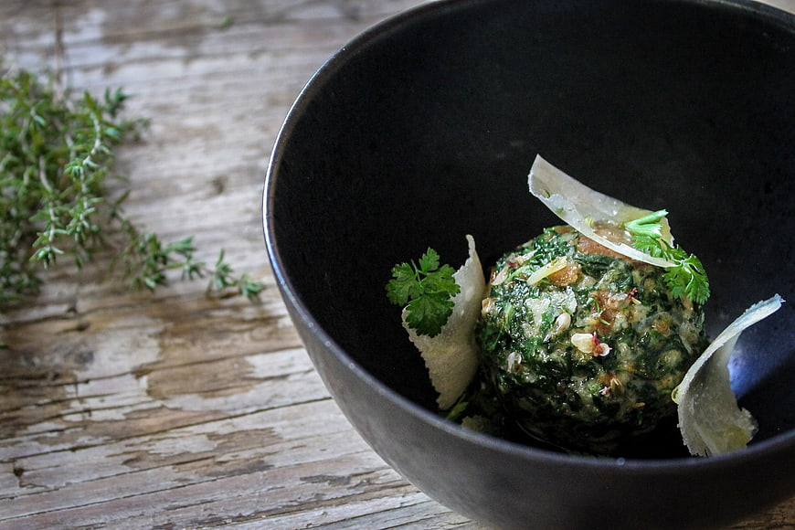 Gourmet spinach dumpling in black bowl on rustic wood