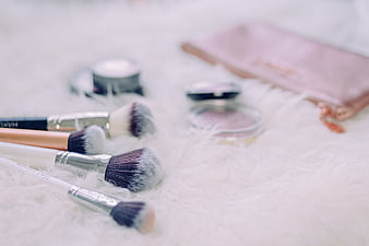 Makeup Brushes and Cosmetics on White Fur Background